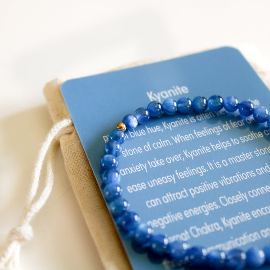 Close-up of a blue Kyanite 4mm gemstone bracelet resting on its meaning card.