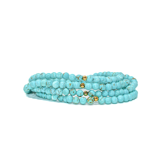 Multiple turquoise gemstone bracelets stacked together, showing natural matrix patterns and gold-filled accent beads.