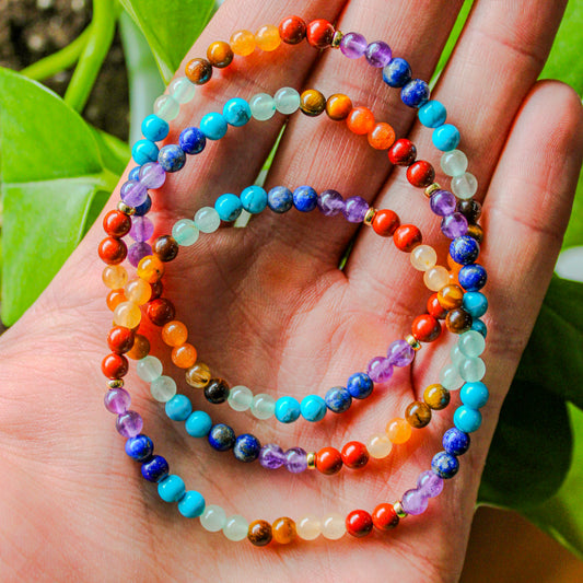 Close-up view of a 7 Chakra bracelet showing the colorful gemstone sequence with a gold-filled accent bead.