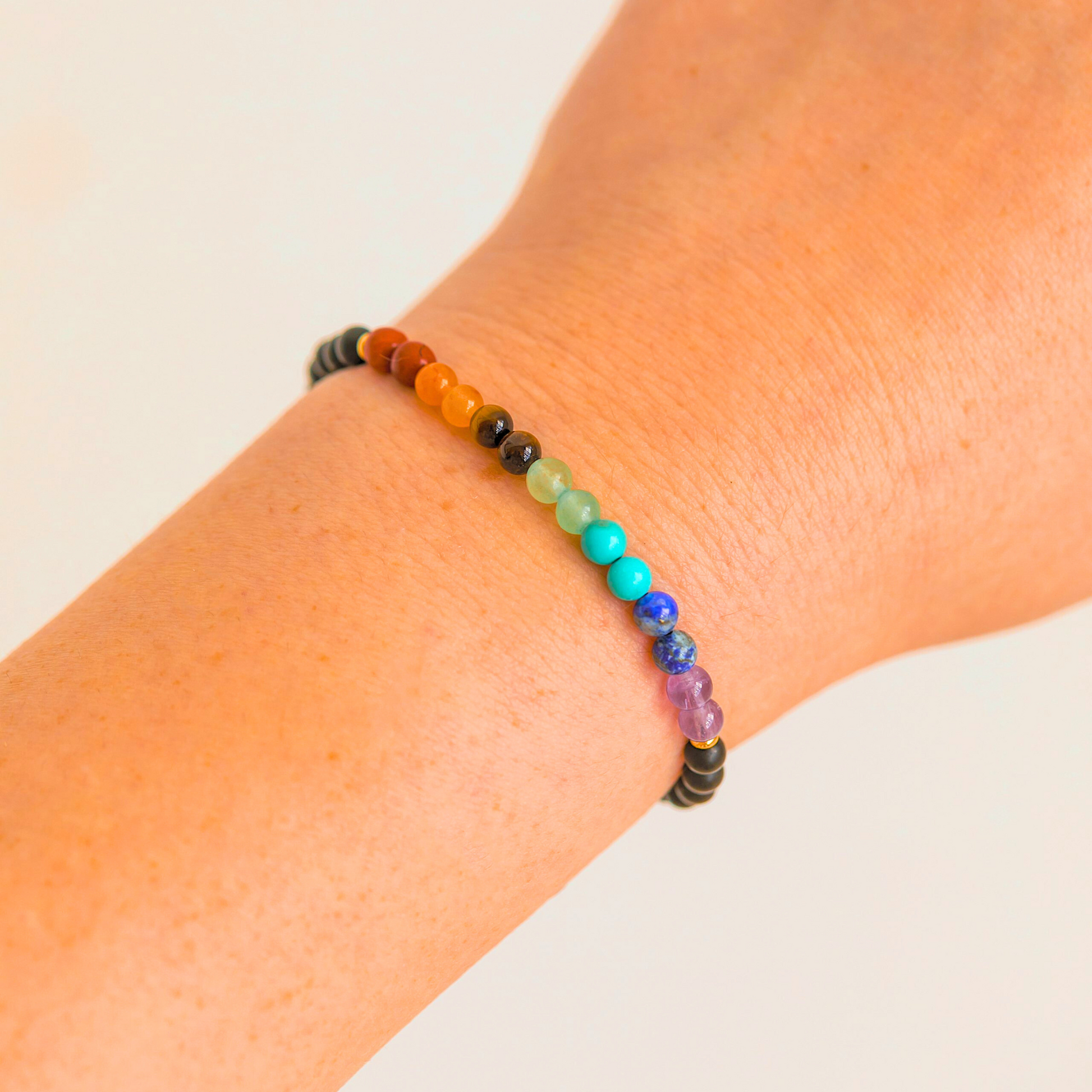 Close-up view of the 7 Chakra crystal bracelet on a wrist, showing the full rainbow of gemstone beads.
