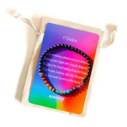 A 7 Chakra gemstone bracelet displayed on a colorful Azenway meaning card atop a linen pouch.