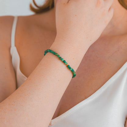 A woman wearing a delicate 4mm African Jade beaded bracelet with a gold accent bead, shown on the wrist for size and fit.