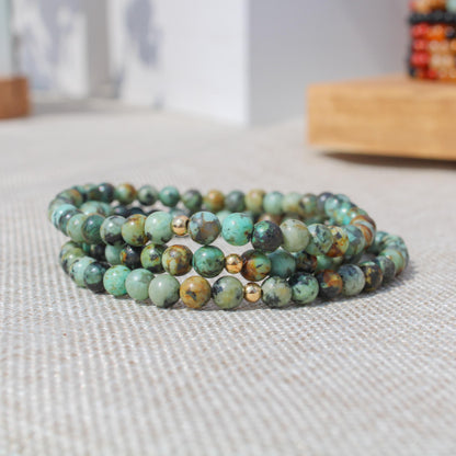 Stack of African Turquoise gemstone bracelets with gold-filled accents shown in natural light.