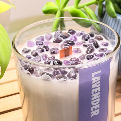 Close detail of amethyst stones embedded in the top of a lavender candle with a wooden wick.