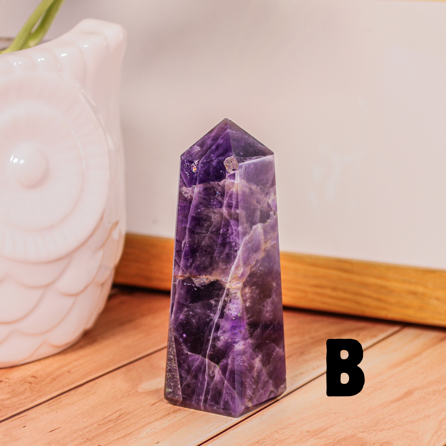 Amethyst crystal tower labeled B polished purple stone point photographed on wooden surface