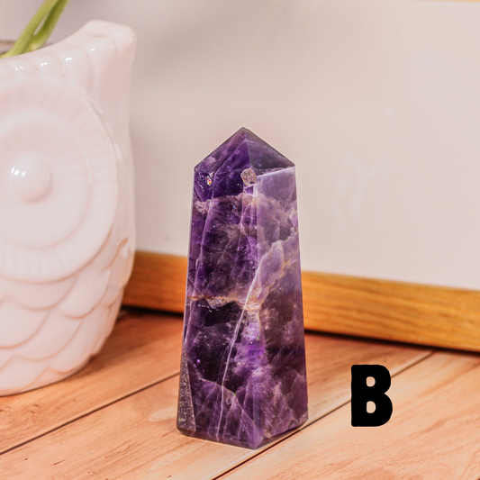 Amethyst crystal tower labeled B polished purple stone point photographed on wooden surface