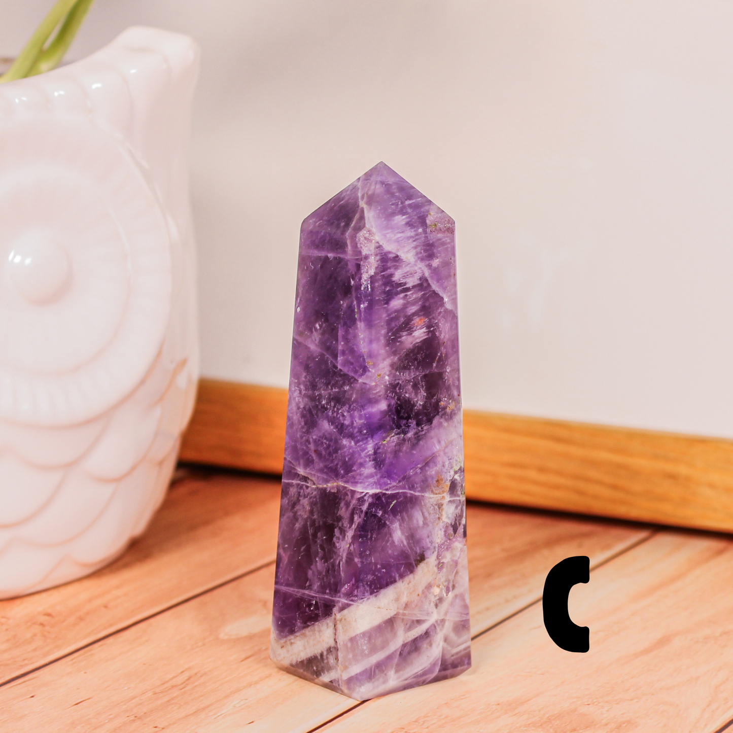 Amethyst crystal tower labeled C polished purple stone point photographed on wooden surface