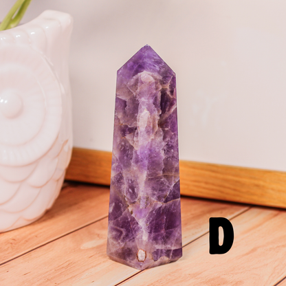 Amethyst crystal tower labeled D polished purple stone point photographed on wooden surface