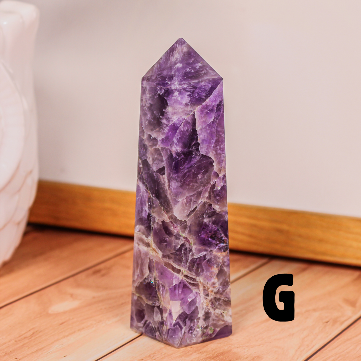Amethyst crystal tower labeled G polished purple stone point photographed on wooden surface