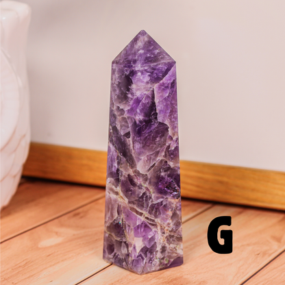 Amethyst crystal tower labeled G polished purple stone point photographed on wooden surface