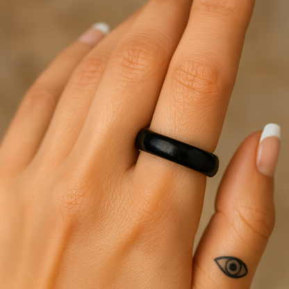 Woman’s hand wearing a Black Obsidian crystal ring — polished natural stone band with minimalist spiritual tattoo