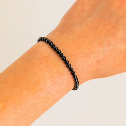 Black Tourmaline 4mm beaded bracelet worn on wrist, minimalist crystal jewelry.