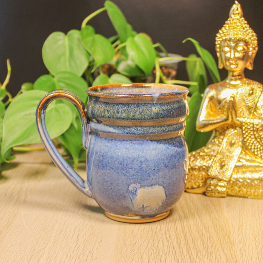 Side view of handmade ceramic blue mug with handle, layered glaze in blue and earth tones by Emma Stewart