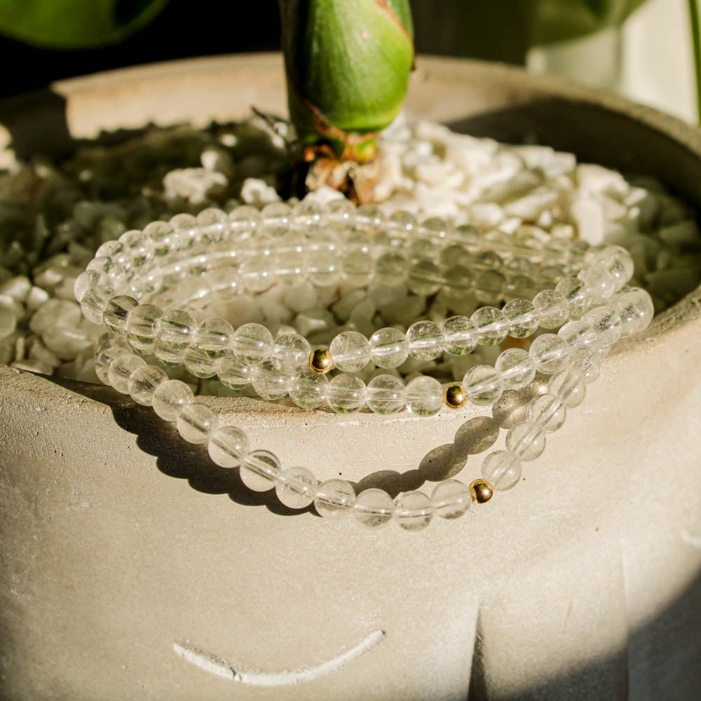 Clear Quartz gemstone bracelets with 14k gold-filled beads styled on a planter for a bright, natural display.