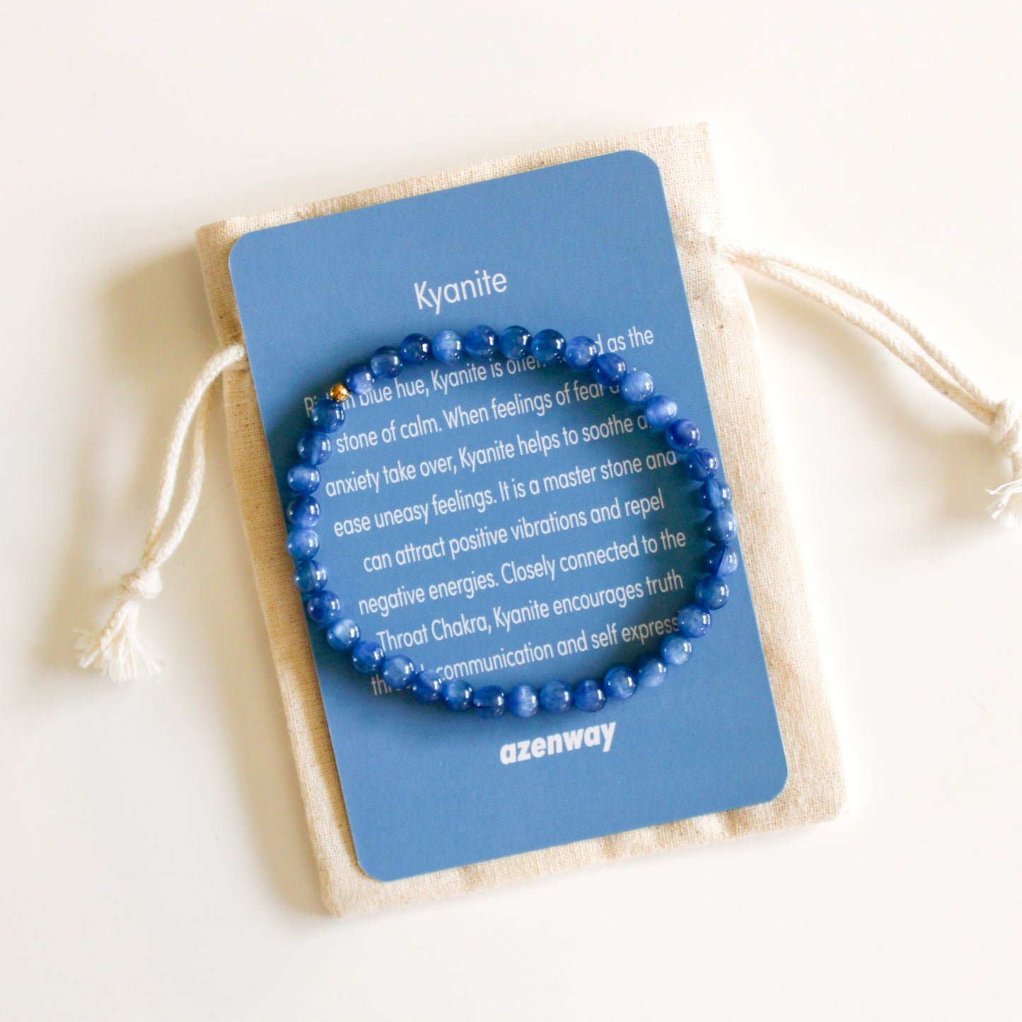 Blue Kyanite 4mm gemstone bracelet displayed on a blue Kyanite meaning card and cream drawstring pouch.