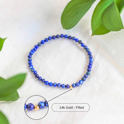 Lapis Lazuli gemstone bracelet with 14k gold filled accent photographed on white linen.