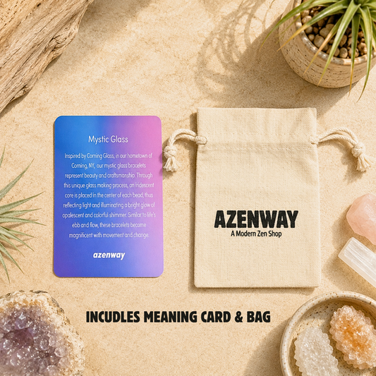 Azenway Mystic Glass bracelet information card displayed beside a natural cotton drawstring pouch on a warm stone surface. Surrounded by crystals, air plant, driftwood, and earthy décor, the flat lay highlights the bracelet's gift-ready packaging in a calming, zen-inspired setting.