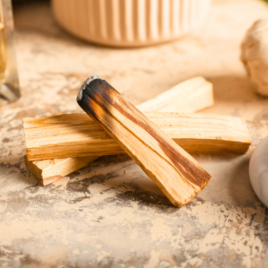 A bundle of hand-cut Peruvian Palo Santo sticks tied with natural twine, resting on a white surface, used for spiritual cleansing, meditation, and energy clearing.