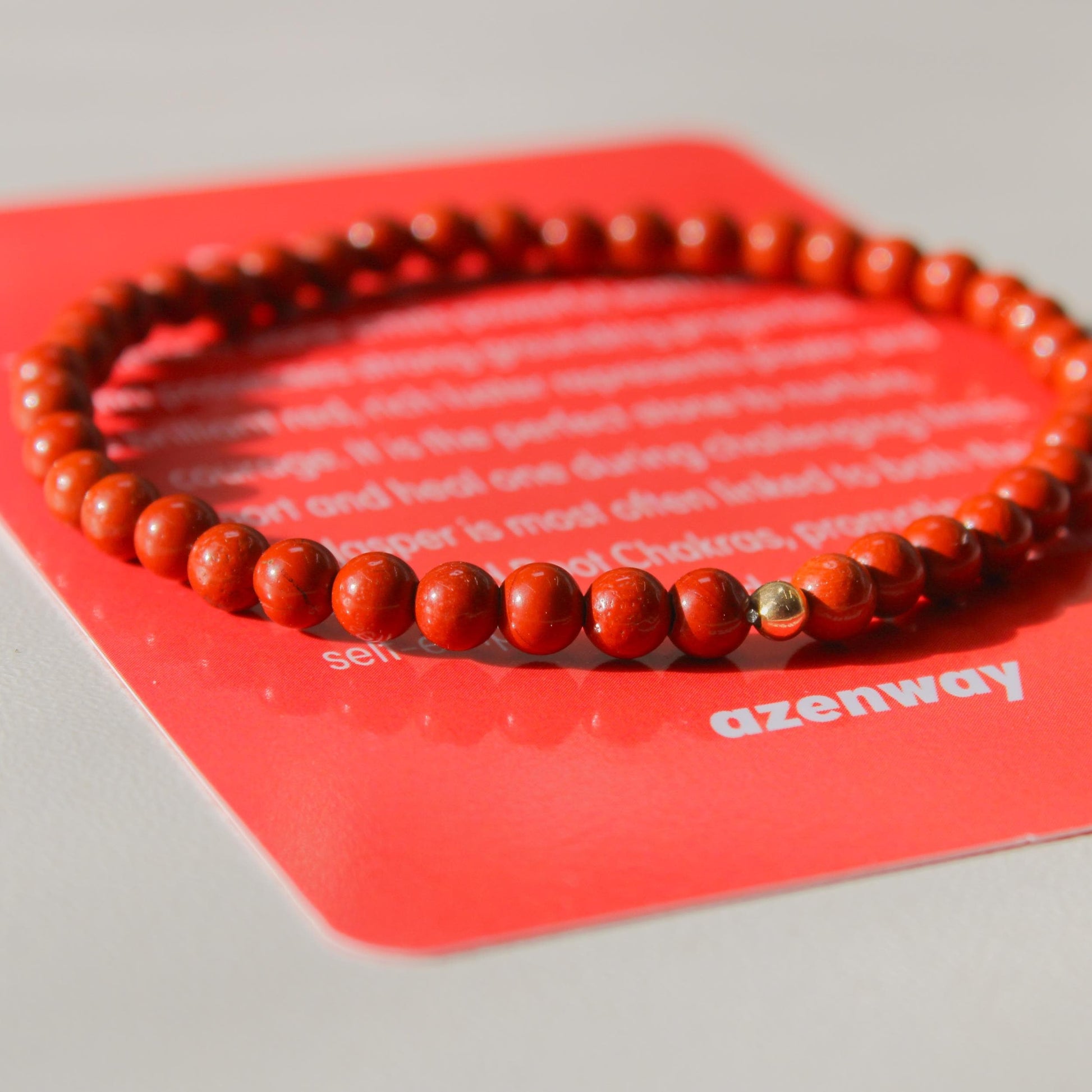 Red Jasper Bracelet on red Azenway meaning card — natural 4mm stones with gold-filled accent