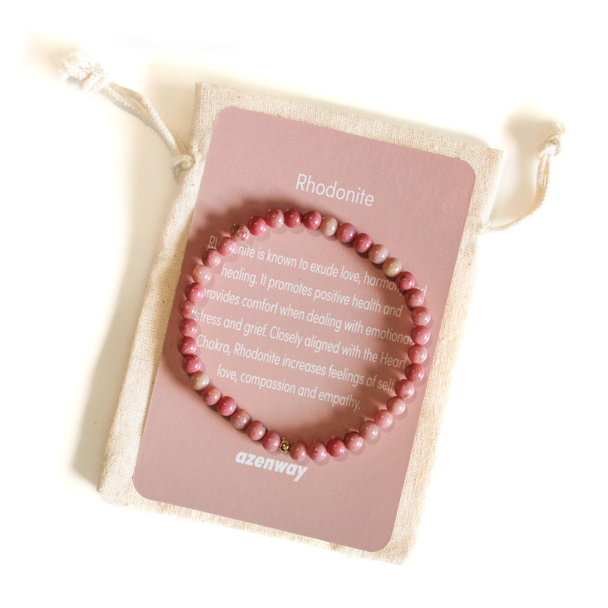 Rhodonite crystal bracelet displayed on an Azenway meaning card and cotton gift bag, showing its soft pink tones and gold accent bead.