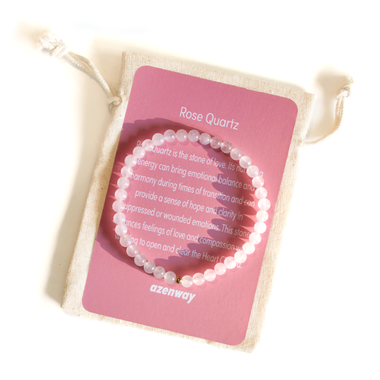 Rose Quartz 4mm beaded bracelet with a single gold-filled bead displayed on top of its pink Azenway meaning card and drawstring pouch.