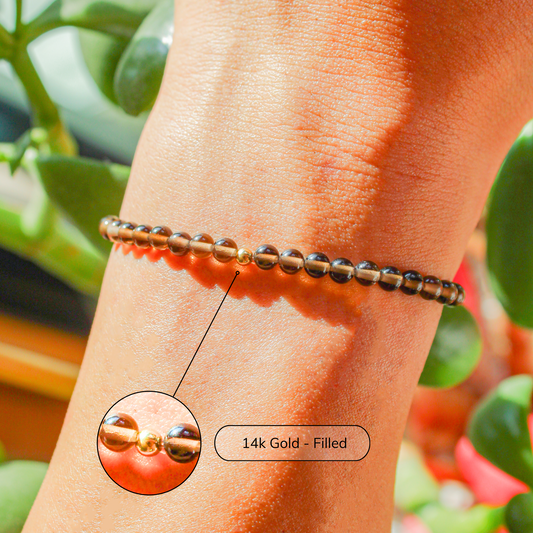 Smoky Quartz bracelet with 14k gold-filled bead shown on wrist in natural sunlight, highlighting the translucent brown stones.