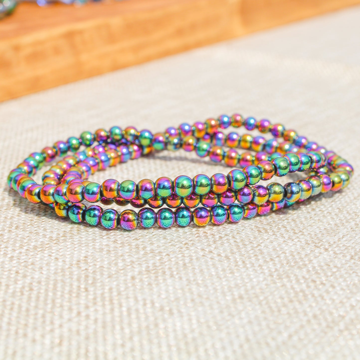 Multiple Rainbow Hematite beaded bracelets stacked together, showing vibrant iridescent colors in bright natural light.