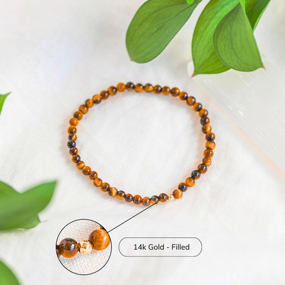 Close-up of Tiger’s Eye bracelet featuring 14k gold-filled accent bead, styled with greenery.