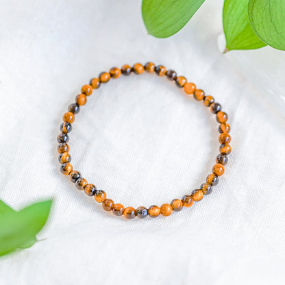 Close-up of the Tiger’s Eye gemstone bracelet with a 14k gold-filled accent bead on a soft white surface.