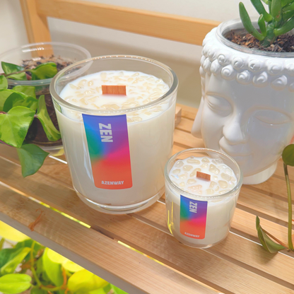 Two Zen essential oil candles with wooden wicks on a bamboo shelf beside plants and a white Buddha planter at Azenway.