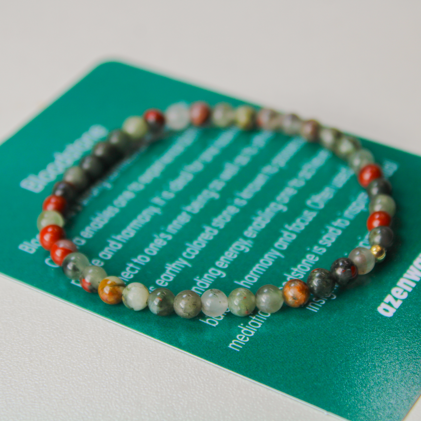 Close-up of Bloodstone gemstone bracelet resting on Azenway meaning card.